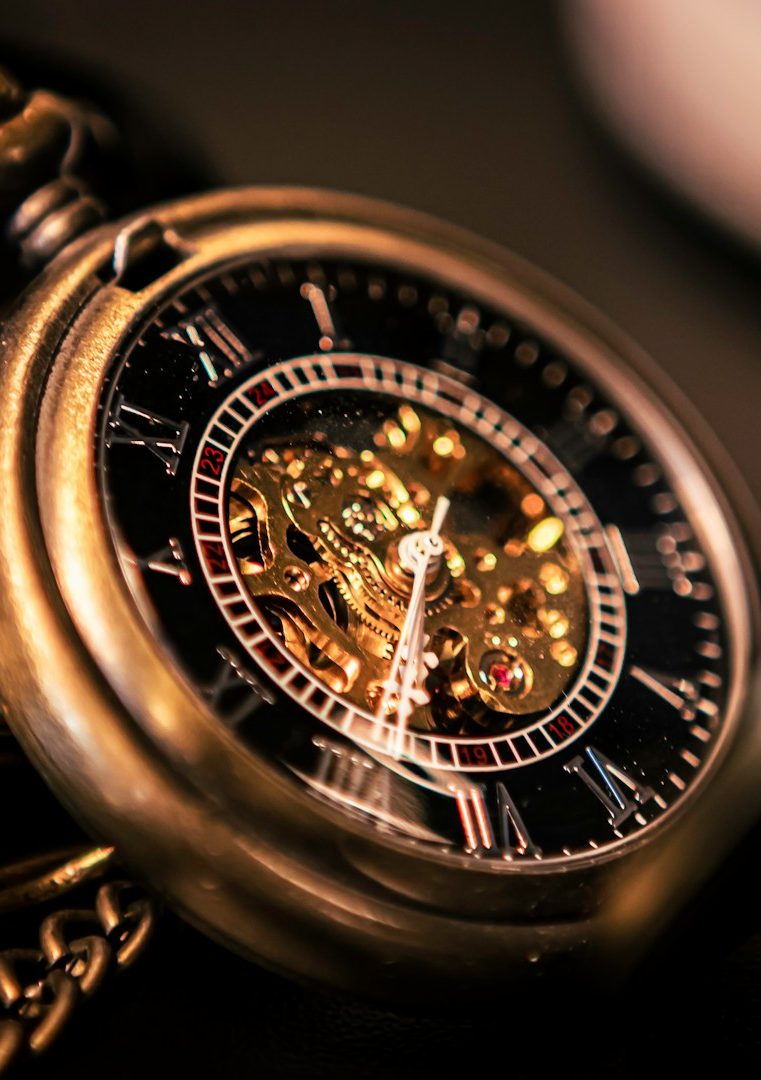 Goldene Taschenuhr mit sichtbarem Uhrwerk auf schwarzem Zifferblatt.