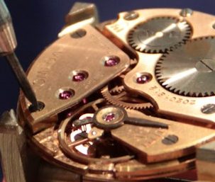 Detailaufnahme eines Uhrenmechanismus mit roten Edelsteinen.